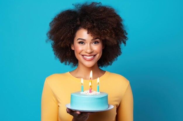 Woman with afro curls holding cake with candles on blue background