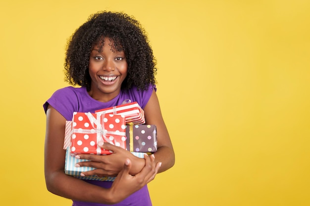 Foto donna con l'acconciatura afro che sorride alla macchina fotografica che tiene i regali