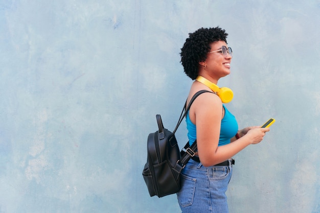 Woman with afro hairstyle walking down the street and holding cell phone