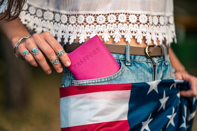 Donna con una bandiera americana e un passaporto in tasca dei jeans