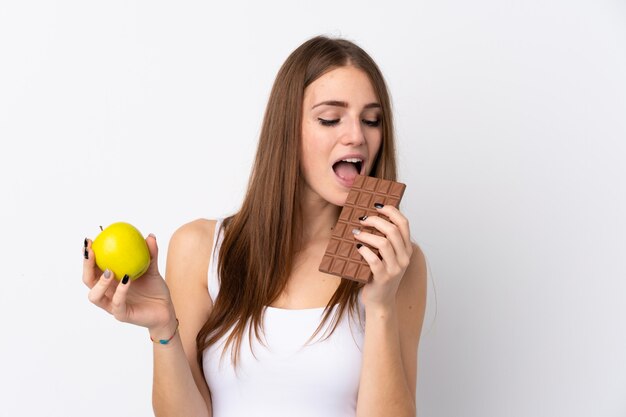 Woman with apple in one hand and chocolate in the other