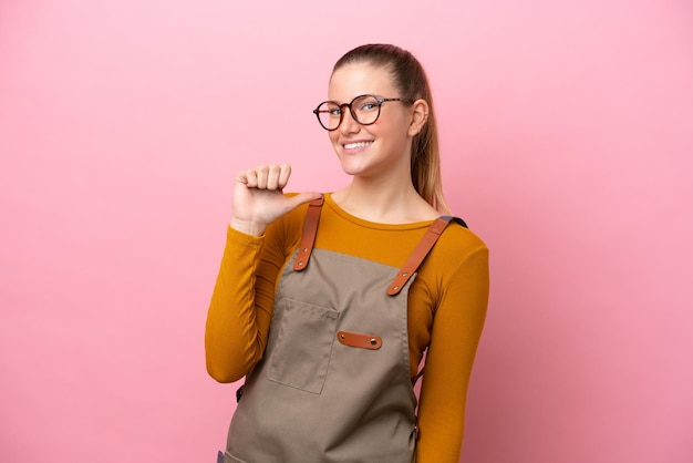 Woman with apron isolated on pink background proud and selfsatisfied