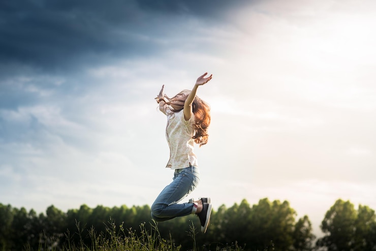 Photo woman with arms outstretched jumping against sky