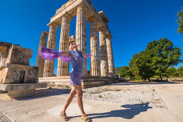 Woman with arms outstretched standing against old ruins