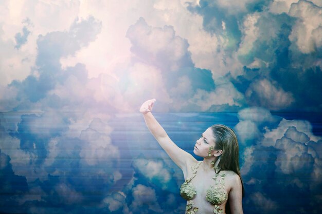 woman with arms raised against sky