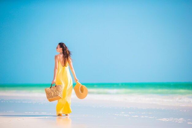 Woman with arms raised on beach against sky