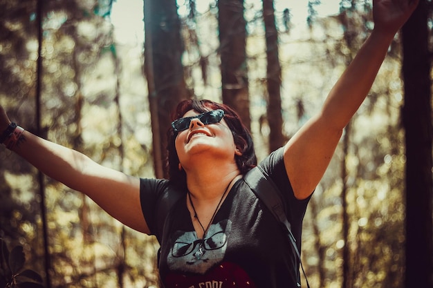 Photo woman with arms raised standing in forest