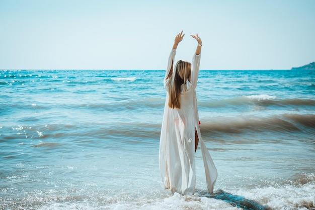 写真 腕を上げて海に立っている女性