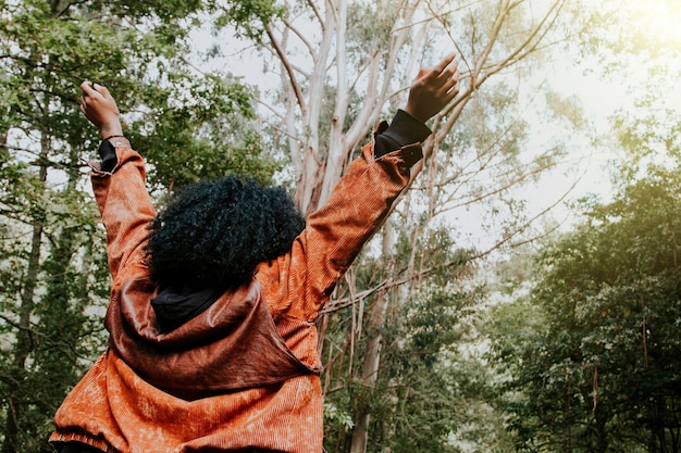 Photo woman with arms upraised getting the sun in the forest