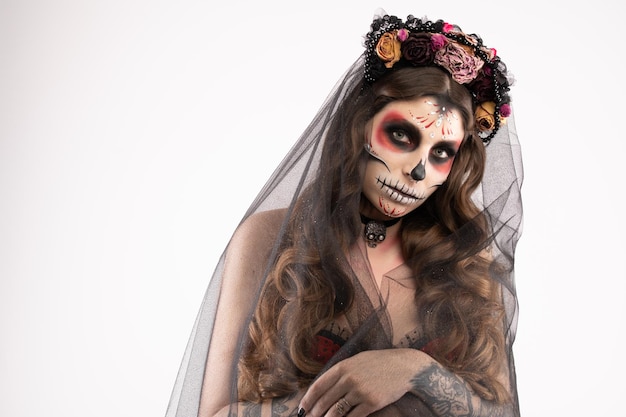 Woman with artistic spooky makeup and fresh flowers on head standing prepared for halloween