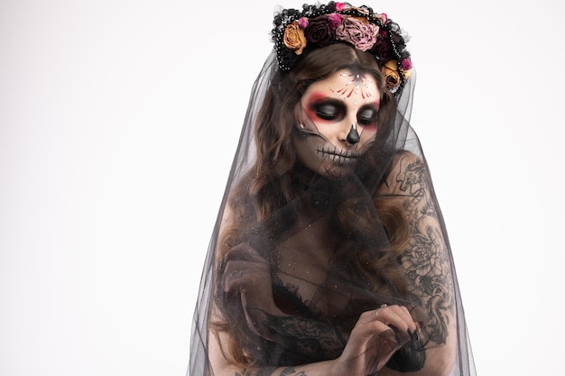 Woman with artistic spooky makeup and fresh flowers on head standing prepared for halloween