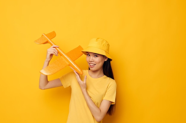 Woman with Asian appearance in a hat with an airplane in his hands model toy isolated background unaltered