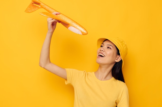 Woman with asian appearance with a yellow plane in his hands a toy isolated background unaltered