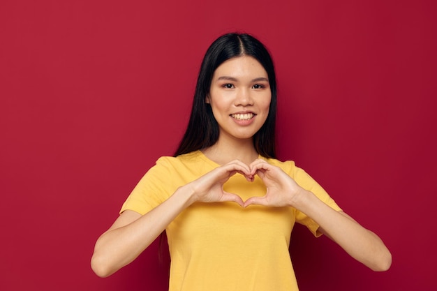 Woman with Asian appearance in a yellow tshirt gesturing with his hands fun isolated background unaltered