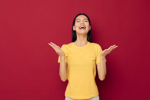 Woman with Asian appearance in a yellow tshirt gesturing with his hands fun isolated background unaltered