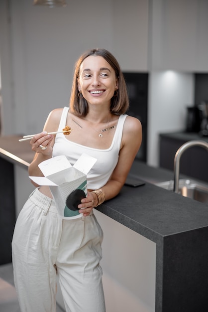 Woman with asian takeaway food at kitchen