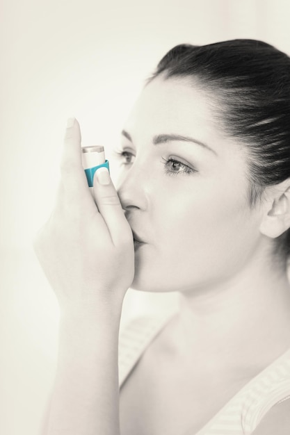 Woman with asthma using an asthma inhaler for preventing attacks