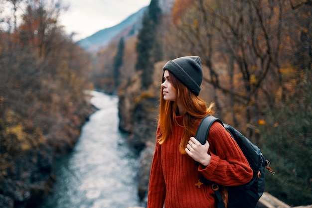 バックパックを持つ女性は山の自然の川を賞賛します