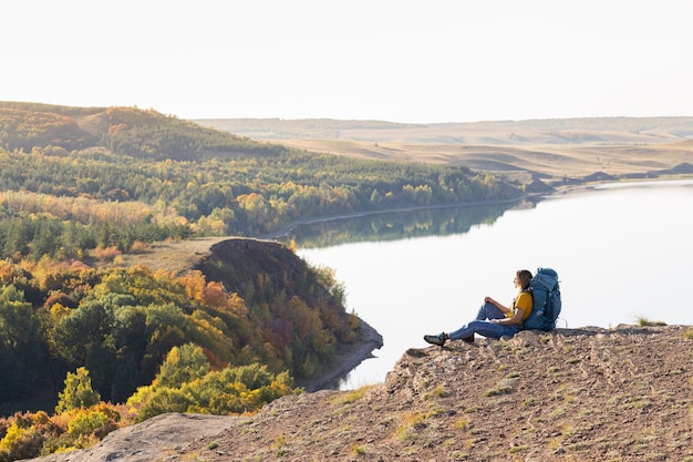 A woman with a backpack on the background of the lake and forest