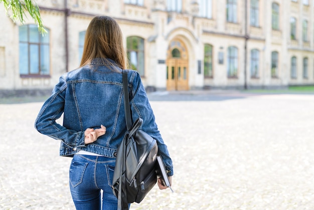 Woman with backpack crossing fingers campus