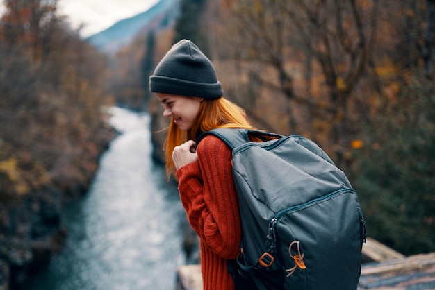 Woman with backpack in forest autumn river nature landscape