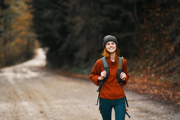 完全な成長のバックパックを背負った女性が秋の森の道を歩いています高品質の写真