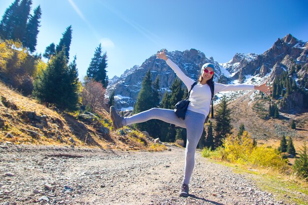 A woman with a backpack is relaxing amid the mountains. Mountain road.