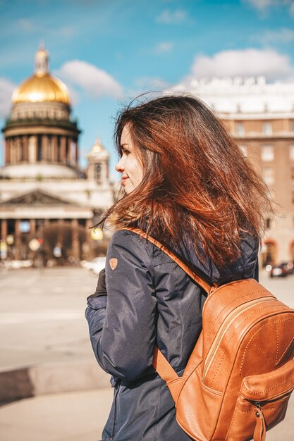 Женщина с рюкзаком, глядя на Исаакиевский собор и главную площадь Санкт-Петербурга