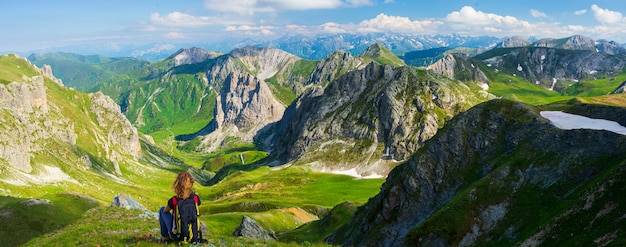 Женщина с рюкзаком, отдыхая на вершине горы