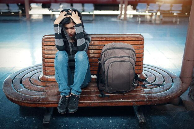 Photo woman with backpack sitting on bench at railroad station