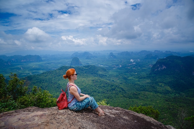 Woman with a backpack sitting on rocks