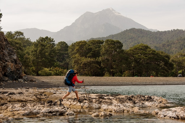 Woman with backpack trekking on a sea shore