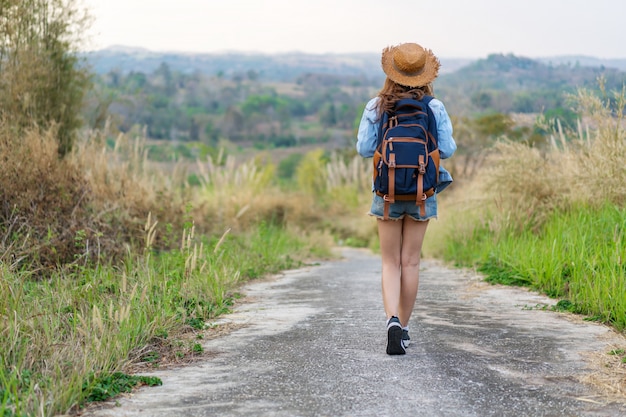 Woman with backpack walking on footpath in nature