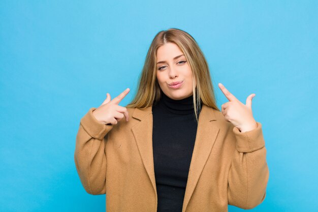 Photo woman with a bad attitude looking proud and aggressive, pointing upwards or making fun sign with hands