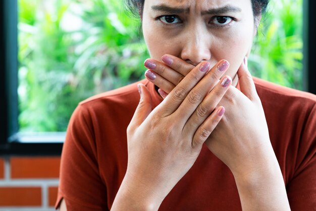 Woman with bad breath covering mouth