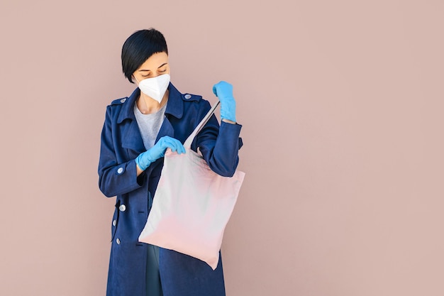 Woman with bag goes shopping. female wearing medical mask and gloves on the street during covid 19 outbreak. protection in prevention for coronavirus