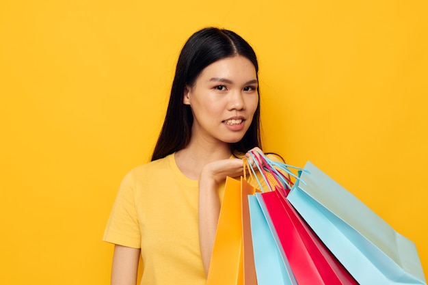 Woman with bags in her hands posing on yellow background