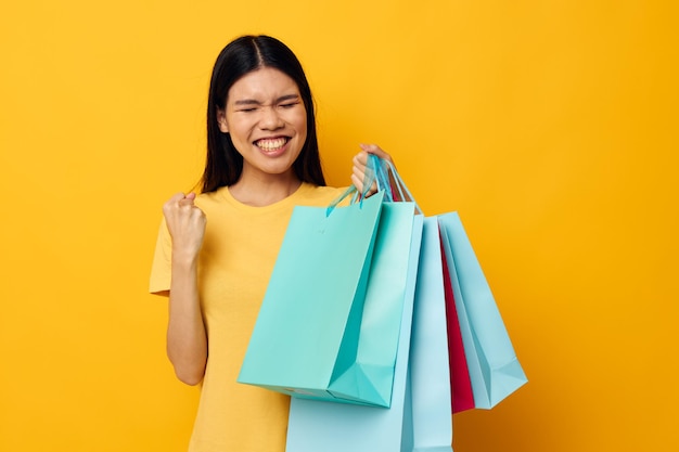 Woman with bags in her hands posing on yellow background