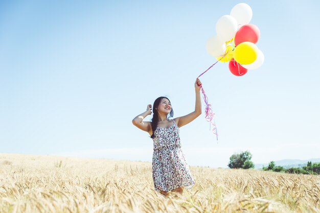 Donna con palloncini in un campo di grano