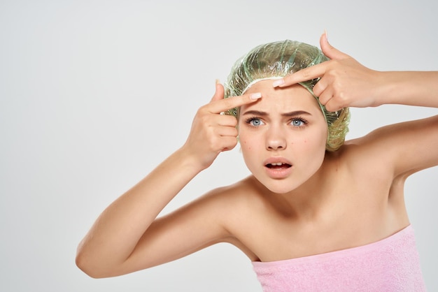 Woman with bare shoulders squeeze acne on her face skin care