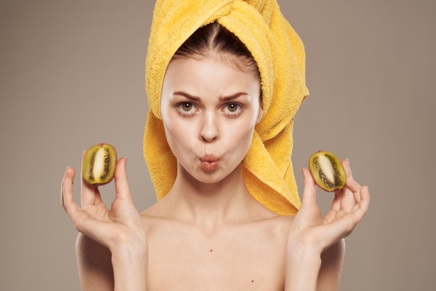 Женщина с голыми плечами с полотенцем на голове киви в руках чистая кожа фруктовая косметика