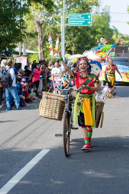 Foto una donna con un cesto in testa cammina per una strada con una bicicletta.