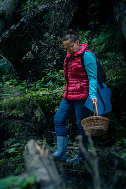 Woman with basket walking by forest looking for mushrooms. copy space