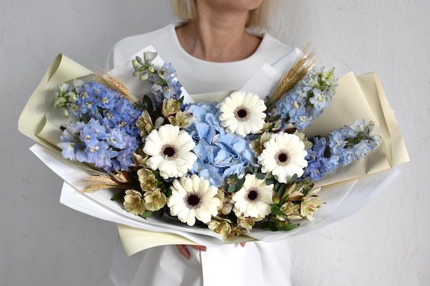 Woman with beautiful flowers in hands indoors background bouquet of flowers for flower shop