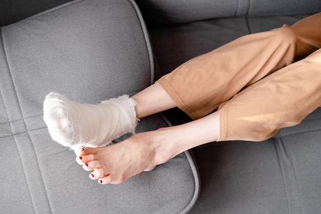 Photo woman with beautiful long legs and a cast on her right leg with crutches lies on the sofa top view