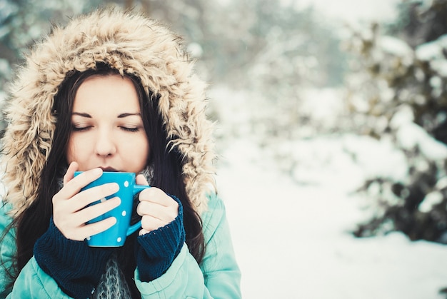 Photo woman with big blue mug of hot drink during cold day.