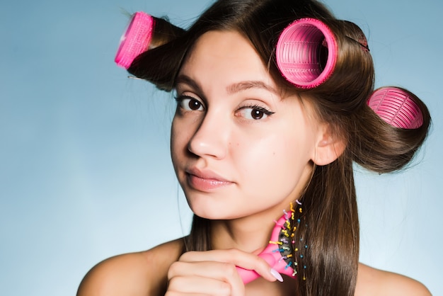 Woman with big curlers on her head combing her hair