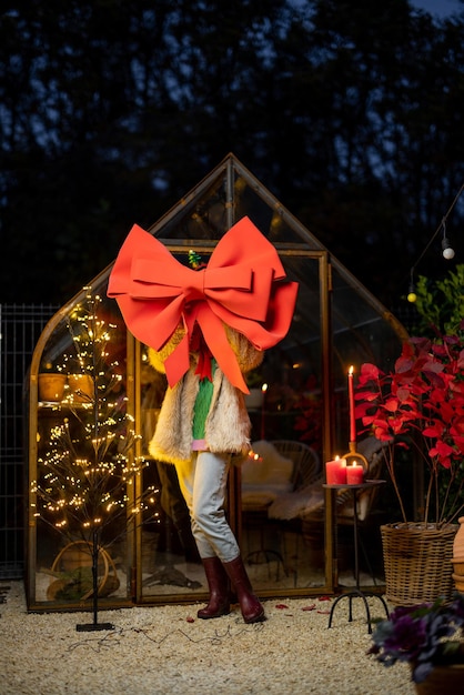 Woman with big festive red bow at backyard