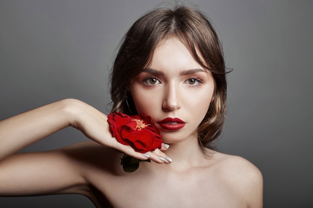 Woman with a big red flower in hair natural makeup