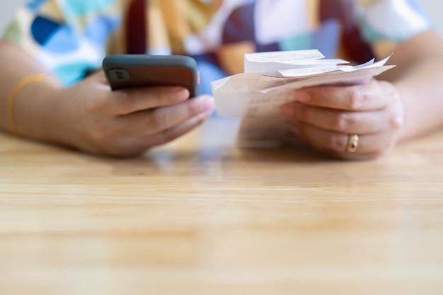 Photo woman with bills and smart phone at the table calculation of costs concept